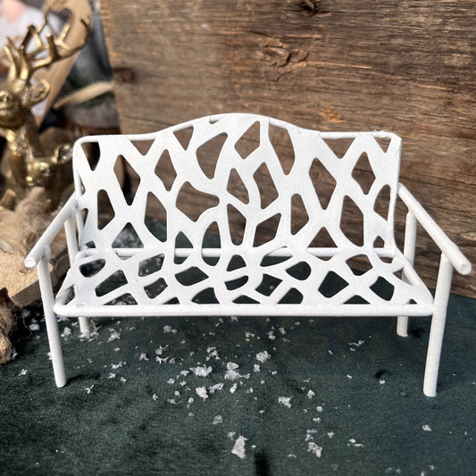 Die weiße Gartenbank aus Metall ist ein passenden Zubehör für die Wichteltür