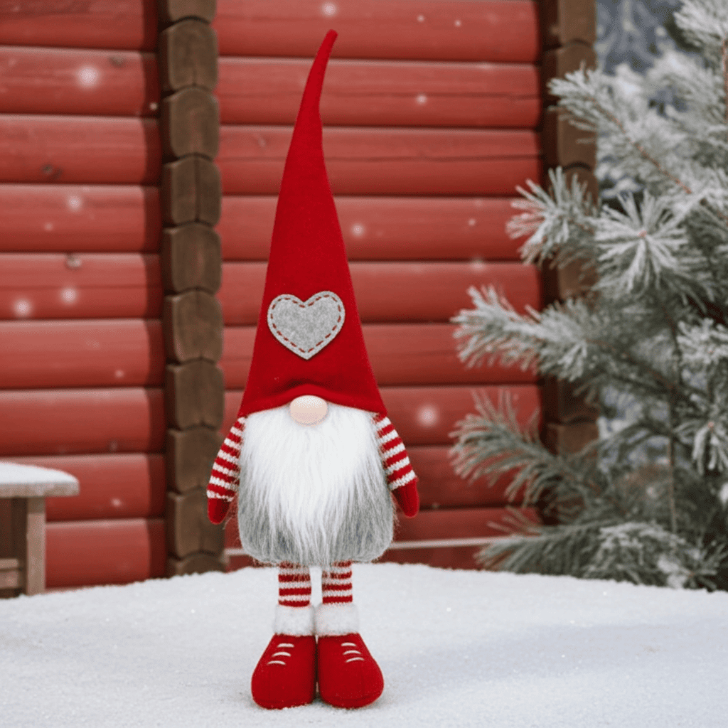 Wichtel - Santa stehend mit grauem Herz auf der Mütze, sowie gestreifte Strickarme und Beine. Der Wichtel besteht aus einem strapazierfähigen Filz und einer Holznase .  
Höhe: ca. 48 cm - Gewicht:&nbsp; ca. 200 g - Material: Filz, Holz - Farben: rot, weiß, grau