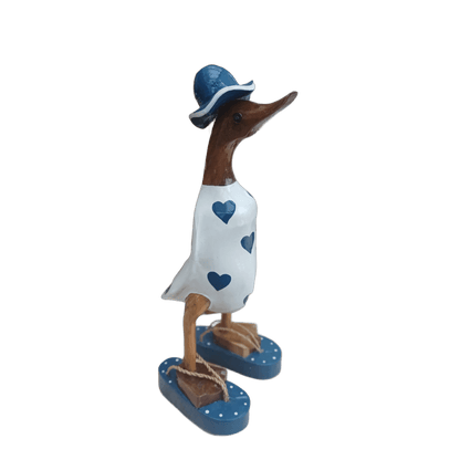 Ente aus Bambus - mit blauen Herzen, blauen Flip Flops und Sonnenhut und einer Höhe von 25 cm. Wunderschöne Deko aus Bambuswurzel. Jedes Teil handgefertigt und ein Unikat. Ein Hingucker für Drinnen und Draußen. 
Ente mit Sonnenhut und Flip Flops in weiß u. blau - Farbe: natur / weiß / blau - Material: Bambus - Maße: Höhe 25 cm - Ursprung: Indonesien. Das Bild ist KI-generiert