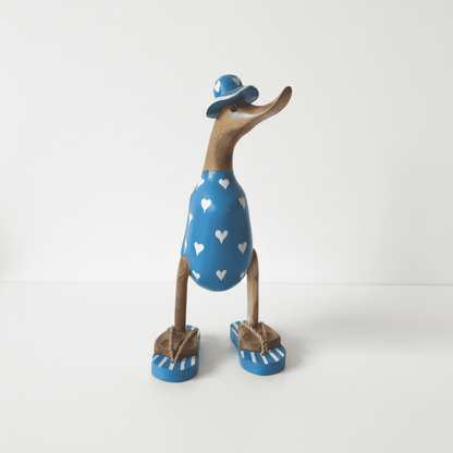 Ente aus Bambus - mit weißen Herzen, blauen Flip Flops und Sonnenhut und einer Höhe von 25 cm. Wunderschöne Deko aus Bambuswurzel. Jedes Teil handgefertigt und ein Unikat. Ein Hingucker für Drinnen und Draußen. 
Ente mit Sonnenhut und Flip Flops in blau mit weißen Herzen - Farbe: natur / blau - Material: Bambus - Maße: Höhe 25 cm